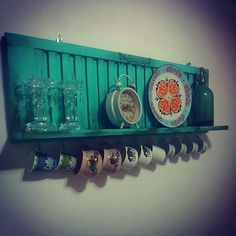 a green shelf filled with lots of cups and saucers on top of a white wall