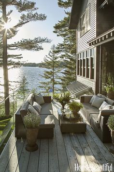 an outdoor living area with couches, tables and potted plants on the deck