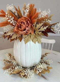 a white pumpkin decorated with flowers and leaves