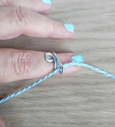 a woman's hand is shown with a ring on top of a string that has been tied to it