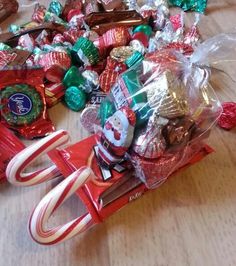 a pile of assorted candy sitting on top of a wooden table next to a pair of scissors