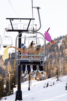 two people riding on a ski lift in the snow