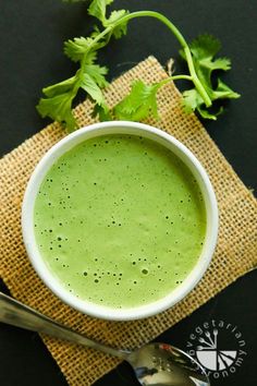 a bowl filled with green liquid next to a spoon