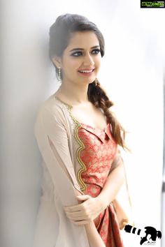 a woman with long hair wearing a dress posing for a photo in front of a white wall