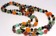 "Long Strand Necklace of Multi Color Glass Beads and Matching Clip Earrings. Glass Bead Colors Are: Orange, Green, Black, White, Gold and Blue Iridescent. Each Color Bead is a Different Shape and Type Such as : Orange-Barrel-Crackel, Green-Oval- Molded Cats Eye, White-Round-Clear, Blue Iridescent Carnival-Round, Gold-Faceted-Round, Etc. Necklace is 50\" Long and Can be Worn Long or Doubled or Tripled. Earrings Are 1\" in diameter and Stamped Made in West Germany. Colorful and Unusual! Necklace a Colorful Glass Beads Jewelry For Party, Colorful Beaded Glass Jewelry For Party, Party Jewelry With Colorful Glass Beads, Multicolor Czech Glass Jewelry For Party, Party Multicolor Faceted Beads Jewelry, Party Jewelry With Round Glass Beads, Multicolor Czech Glass Party Jewelry, Multicolor Beads For Party Costume Jewelry, Multicolor Beads For Costume Jewelry Party