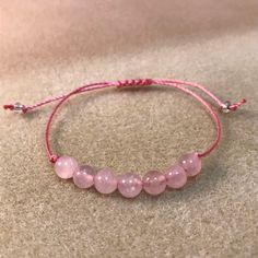 These soft pink rose quartz bracelets are fashionable and healing! Rugged and durable for 24/7 wear, but, still dainty, natural and feminine for her, this rose quartz bracelet is perfect for the whole family, gift giving. party favors, wedding parties and even for a gender reveal! This genuine gemstone bracelet features seven round 6mm rose quartz beads in the center of a comfy knotted bracelet. This trendy string bracelet is strung on durable high quality heavy braided nylon cord with a sliding Pink Adjustable Spiritual Braided Bracelet, Casual Pink Braided Bracelets As Gift, Pink Adjustable Spiritual Friendship Bracelets, Adjustable Pink Spiritual Friendship Bracelets, Adjustable Rose Quartz Jewelry With 8mm Beads, Adjustable Rose Quartz Beaded Jewelry, Casual Pink Bracelets With Natural Stones, Pink Beaded Bracelets With Adjustable Cord As Gift, Pink Natural Stone Bracelets For Friendship