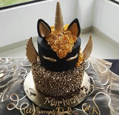 a three tiered cake decorated with gold and black frosting