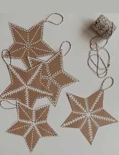 three brown and white paper stars are hanging from twine