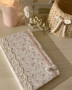 a small book with lace on it sitting next to a candle and some vases