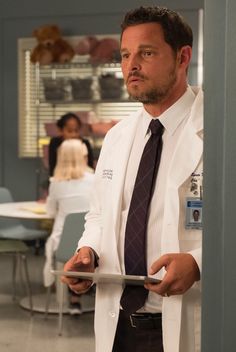 a man in a white coat and tie holding a tablet