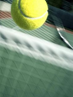 a tennis ball is hitting the net with it's racquet in mid air