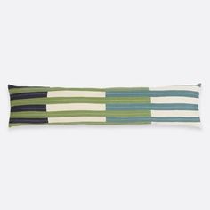 a green and blue striped pillow sitting on top of a white wall