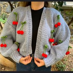 a woman wearing a gray cardigan with cherries on it