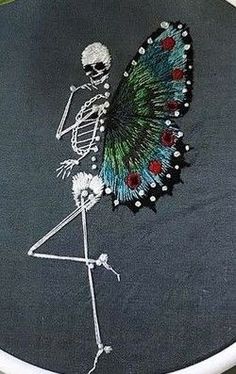 a cross stitched picture of a skeleton with a butterfly on it's back