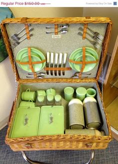 an open wicker suitcase with green dishes and utensils in it on a carpeted floor