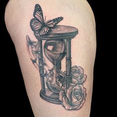 a woman's thigh with an hourglass and roses tattoo on the side of her leg