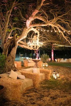 hay bales and candles are placed under the trees in front of an outdoor seating area