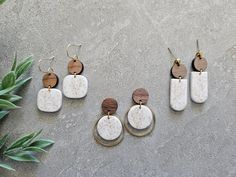 four different types of earrings sitting on top of a cement floor next to a potted plant