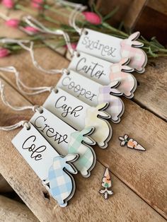 three tags that are sitting on top of a wooden table with flowers in the background