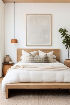 a bed with white linens and pillows in a bedroom next to a painting on the wall