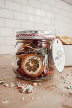 a jar filled with candy canes sitting on top of a wooden table next to a container