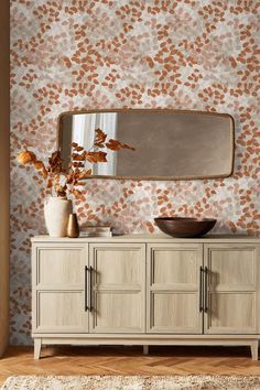 a room with a mirror, dresser and vase on top of the cabinet in front of it