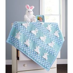 a stuffed bunny sitting on top of a dresser next to a window with blue and white flowers