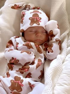 a baby wrapped in a teddy bear blanket sleeping on top of a white blanketed bed