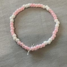 White and pink stretchy seed bead bracelet Pink Pearl Bracelet With Tiny Round Beads, Flexible White Bracelets With Colorful Beads, Pink Friendship Bracelets With Faceted Beads, Casual Pink Beaded Bracelets With Faceted Beads, Handmade White Beaded Flexible Bracelets, Handmade Flexible White Bracelets, Flexible Pink Beaded Bracelet, Flexible Pink Beaded Bracelets, White Beaded Bracelet With Letter Beads