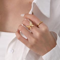 ✦ Indulge in the elegance of our Chunky 18K Gold Butterfly Cocktail Ring made with molten design and 18k gold plating. Perfect for any occasion, this statement ring features a bold butterfly design, adjustable fit, and serves as a luxurious gift for friends. Elevate your style with this exclusive piece that exudes sophistication and uniqueness. ----------- DETAILS ----------- - Color: Gold - Ring Size: 17.3mm (Approximately to Size US7) - Width: 1.8cm - Materials: 18K Gold Plated, Cubic Zirconia Adjustable Gold Butterfly Ring, Gold Formal Butterfly Ring, Adjustable Gold Butterfly Open Ring, Luxury Gold Butterfly Ring, Elegant Adjustable Gold Butterfly Ring, Luxury Gold Butterfly-shaped Ring, Elegant Gothic, Nose Rings Hoop, Crystal Hoop Earrings