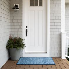 a white door with a blue rug on the front porch