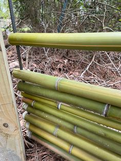 several bamboo poles stacked on top of each other in front of some bushes and trees