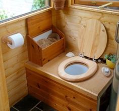 a wooden toilet in a small bathroom next to a window and trash can on the counter