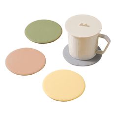 three different colored coasters sitting next to each other on a white surface with a coffee cup in the middle