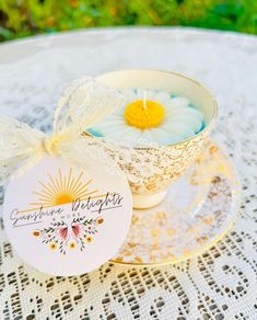 a teacup with a candle in it on a lace doily next to a tag