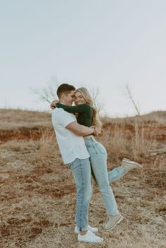 a man and woman hugging in the middle of a field