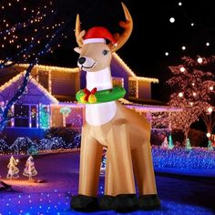 an inflatable deer with a christmas hat on it's head is standing in front of a house