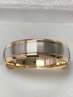 two tone gold and silver wedding ring on white background with satin fabric in the background