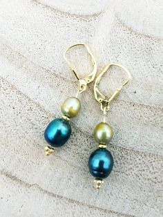 Earrings made of 14 carat gold plated Sterling silver with light olive green and blue freshwater pearls. Total length including ear hook:  3.5 cm Blue Drop Pearl Earrings With Pearl Charm, Green Pearl Charm Drop Earrings, Green Dangle Pearl Earrings With Ear Wire, Green Dangle Pearl Earrings, Green Drop Earrings With Pearl Charm, Elegant Green Pearl Charm Earrings, Elegant Green Pearl Earrings With Charm, Green Pearl Dangle Earrings, Green Pearl Drop Earrings