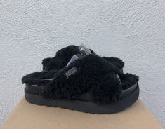 UGG FUZZ SUGAR CROSS SLIDE SLIPPERS/ SANDALS ~ NEW  WOMEN'S SIZE US 9/ EUR 40/ UK 7 MADE FROM ENVIRONMENTALLY FRIENDLY PLANT BASED MATERIALS AND REPURPOSED WOOL  COLOR: BLACK ~MY ITEMS ARE ALWAYS AUTHENTIC, PLEASE SEE MY TRUSTED FEEDBACK Both indoor and outdoor use Fully covered with Repurposed wool and faux fur ( lyocell) UGG logo Repurposed wool and faux fur ( lyocell) insole Sugarsole foam sole ( made from sugarcane) Please see the pictures for more detail Inside size tag has been marked to prevent retail store returns Please note, most UGGs are now made in China, Vietnam, Philippines or Cambodia. NONE are made in Australia PLEASE SEE MY OTHER LISTINGS  PLEASE READ: MY ITEMS ARE ALWAYS AUTHENTIC, PLEASE NOTE THE PLANT BASED STYLE'S DO NOT HAVE THE HOLOGRAMS AS THE HOLOGRAM MATERIAL IS N Black Ugg Slippers, Black Uggs, Slide Slippers, Faux Fur Slippers, Ugg Black, Ugg Slippers, Fur Slippers, Slipper Sandals, Dream Clothes