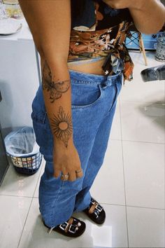 a woman with tattoos on her arm and foot standing in front of a counter top