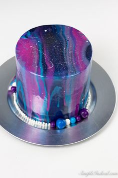 a purple and blue marble cake on a silver platter with beaded trims