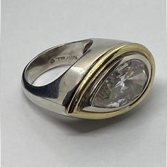 a close up of a ring with a diamond in the center and two tone gold accents