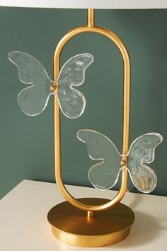 a lamp with two glass butterflies on it's base and a white light in the background