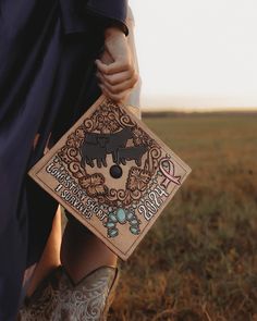 a woman in boots holding a wooden block with an image of two cows on it