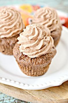 three chocolate cupcakes with frosting on a white plate