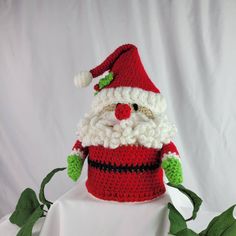 a crocheted santa clause hat sitting on top of a white cloth covered table