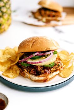 a pulled pork sandwich on a plate with potato chips