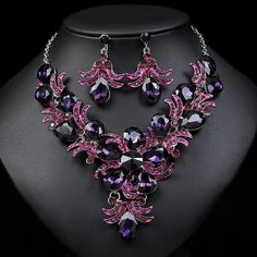 a necklace and earring set with purple crystals on a black mannequins