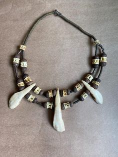 Unique one of a kind necklace made from African trade beads of clay and brass. The teeth are from camel and it all comes together with snake vertebra. An easy hook and eye closure makes for ease when putting on and taking off. This statement piece is focused on ancient trade craft based on how ancient peoples adorned themselves. Unique Adjustable Bone-colored Necklace, Handmade Bone-colored Unique Necklace, Unique Adjustable Bone Colored Necklace, Handmade Bohemian Bone Beaded Necklaces, Unique Handmade Bone-colored Necklace, Unique Adjustable Bone Necklace, Unique Handmade Bone Necklace, Bone Color Bohemian Adjustable Necklace, Polymore Clay